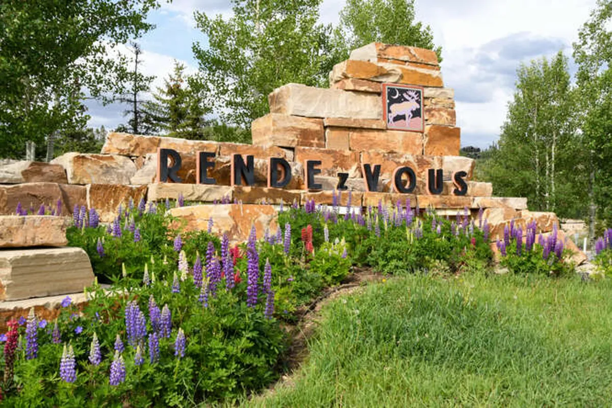 A stone sign surrounded by lush flower beds and green grass, set outdoors. The scene suggests a welcoming entry point to the property or community, inviting guests to enjoy the environment and setting the tone for an eco-conscious and well-maintained retreat.